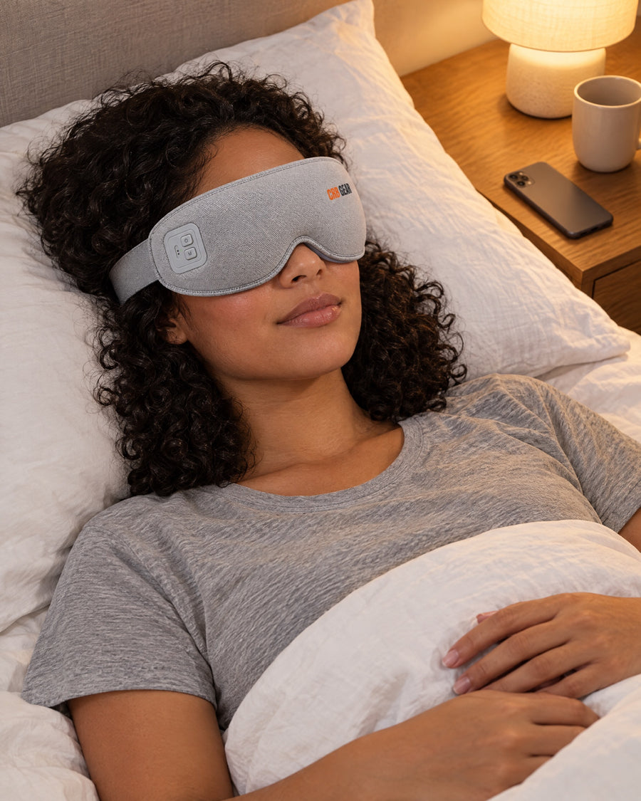 Woman lying in bed wearing the CRB GEAR Reset with her phone face-down on the nightstand